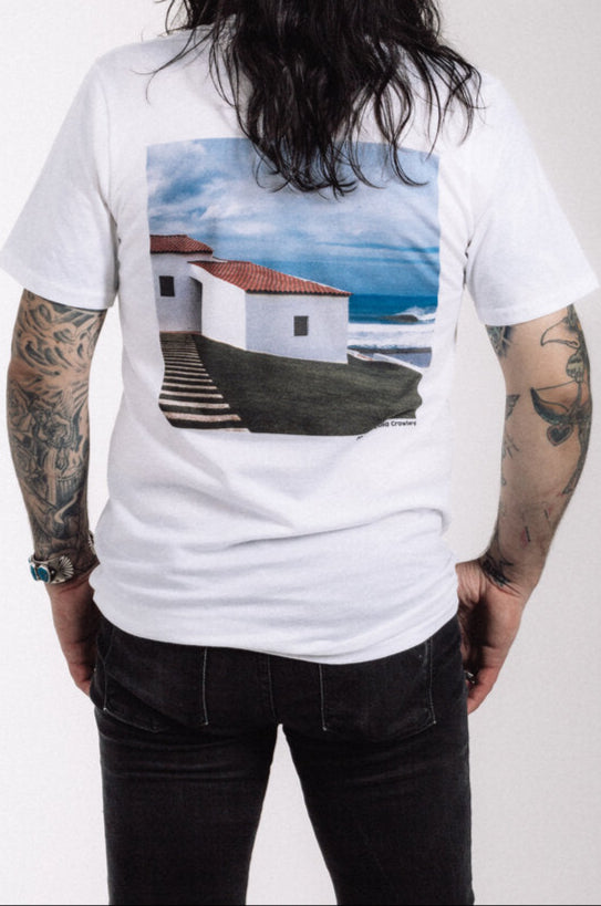 White Puerto band T-shirt with EP Portugal cover artwork featuring coastal building, ocean, and sky, photography by Julia Crowley, legendary surf photographer featured in Surfer Magazine