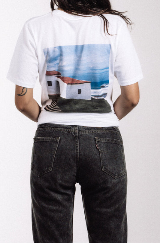 White Puerto band T-shirt with EP Portugal cover artwork featuring coastal building, ocean, and sky, photography by Julia Crowley, legendary surf photographer featured in Surfer Magazine